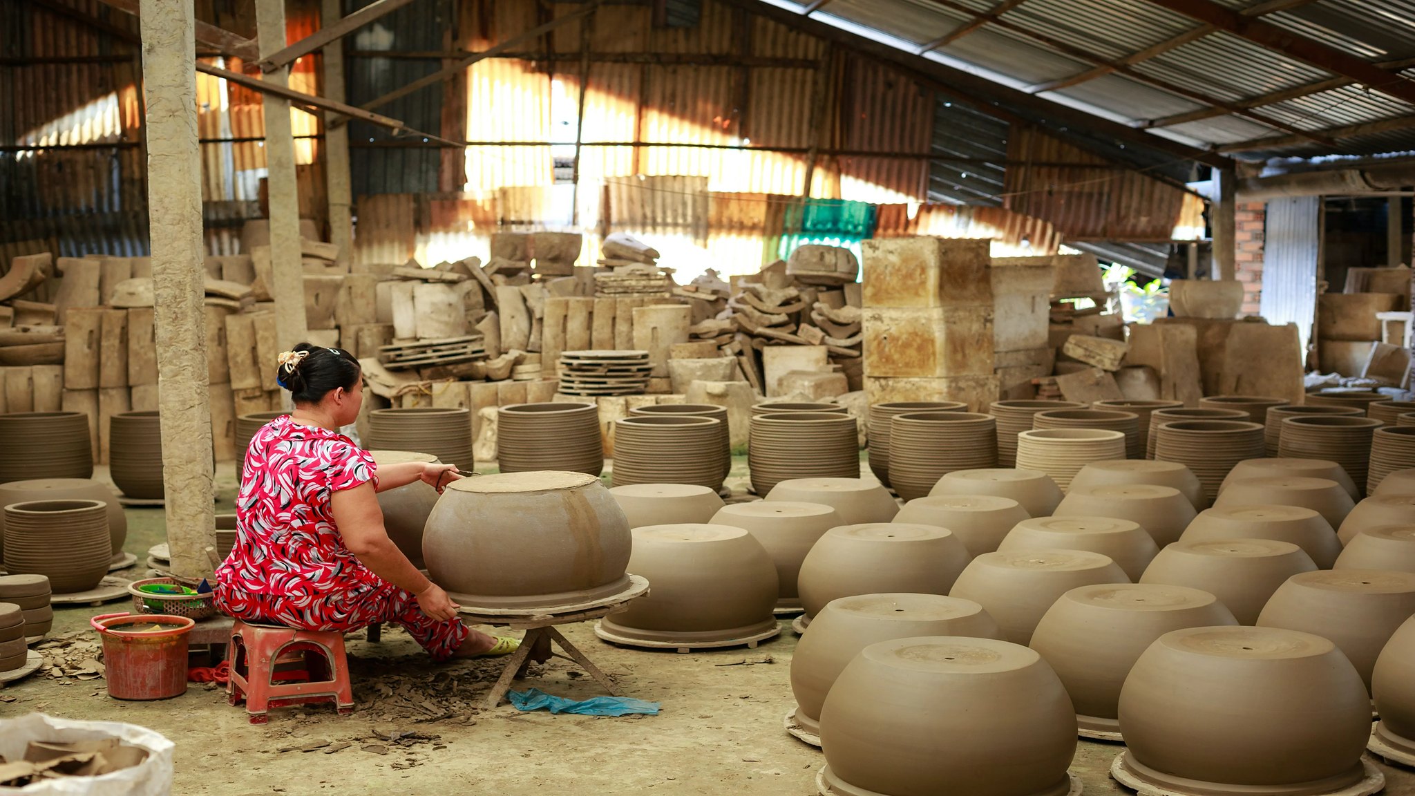 Potter at work among clay pots in a Bat Trang workshop