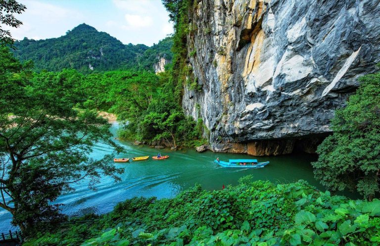 Boats on the Son River below the limestone cliffs of Phong Nha - Rose Travel